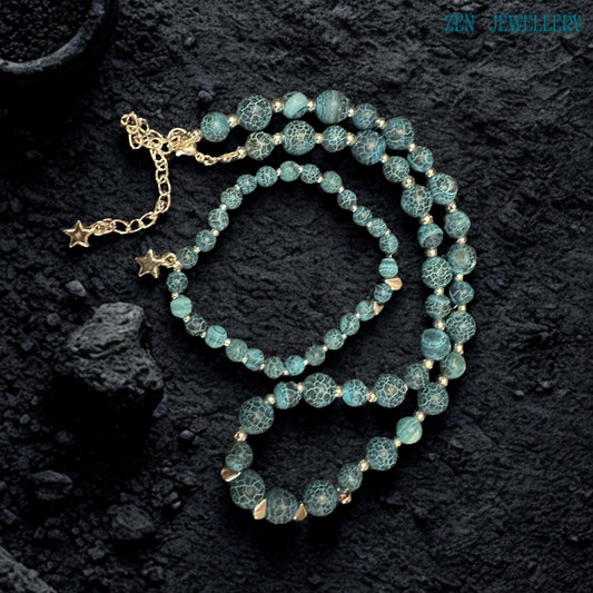 Handmade celestial jewellery set photographed in soft lighting to emphasize the natural crackled patterns within the Blue Crackle Agate gemstone beads featuring deep ocean blue, turquoise, and black tones combined with polished silver accents and star charms creating a mystical bohemian aesthetic inspired by nature, the night sky, and artisan gemstone jewellery craftsmanship.