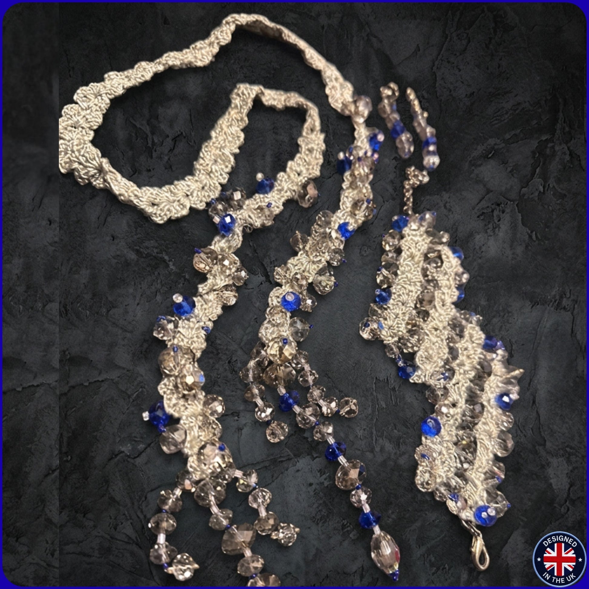 A long beaded necklace with textured silver-toned links, clear faceted beads, and royal blue beads.