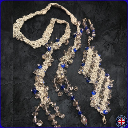 A long beaded necklace with textured silver-toned links, clear faceted beads, and royal blue beads.