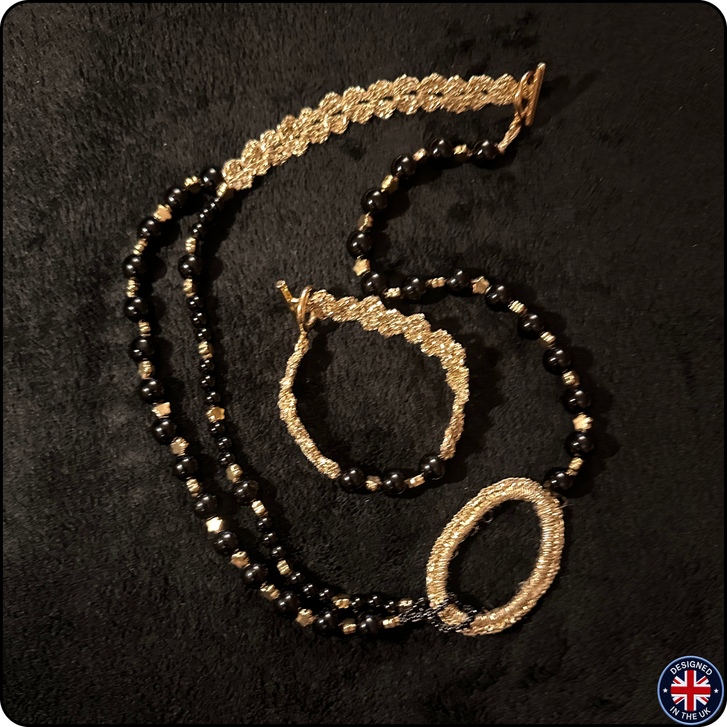 A jewelry set featuring a beaded necklace, bracelet, and matching headband, crafted with black faceted beads and textured gold-toned metal. The necklace has a large oval pendant, and the bracelet features a textured circular clasp.