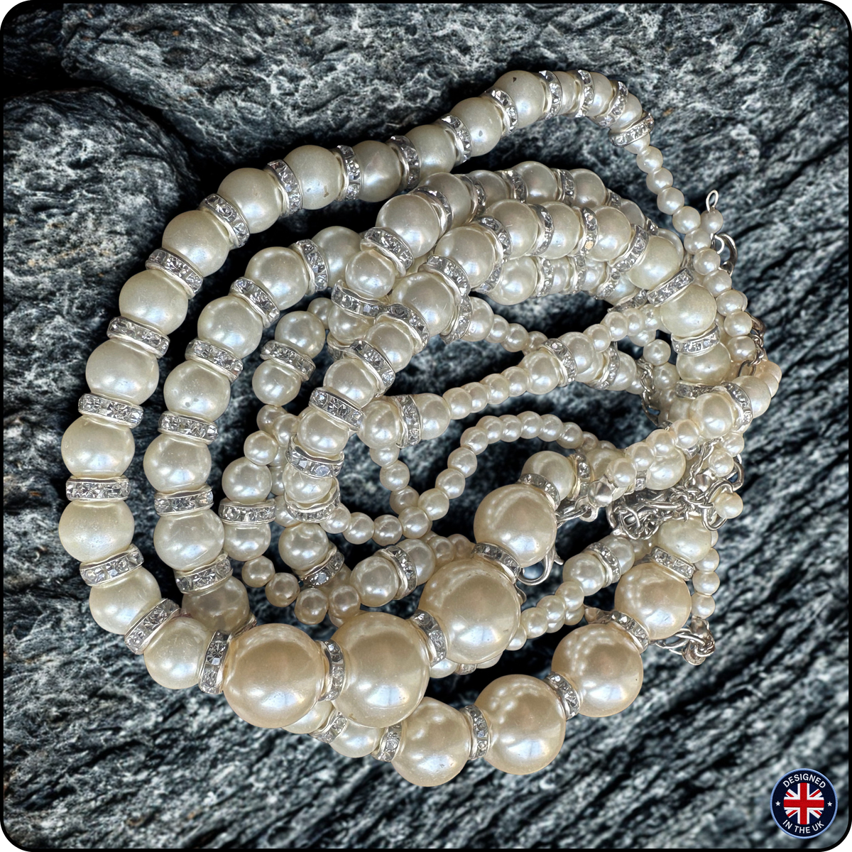 A multi-strand pearl necklace with silver spacer beads, arranged in loops on a dark gray textured stone background.
