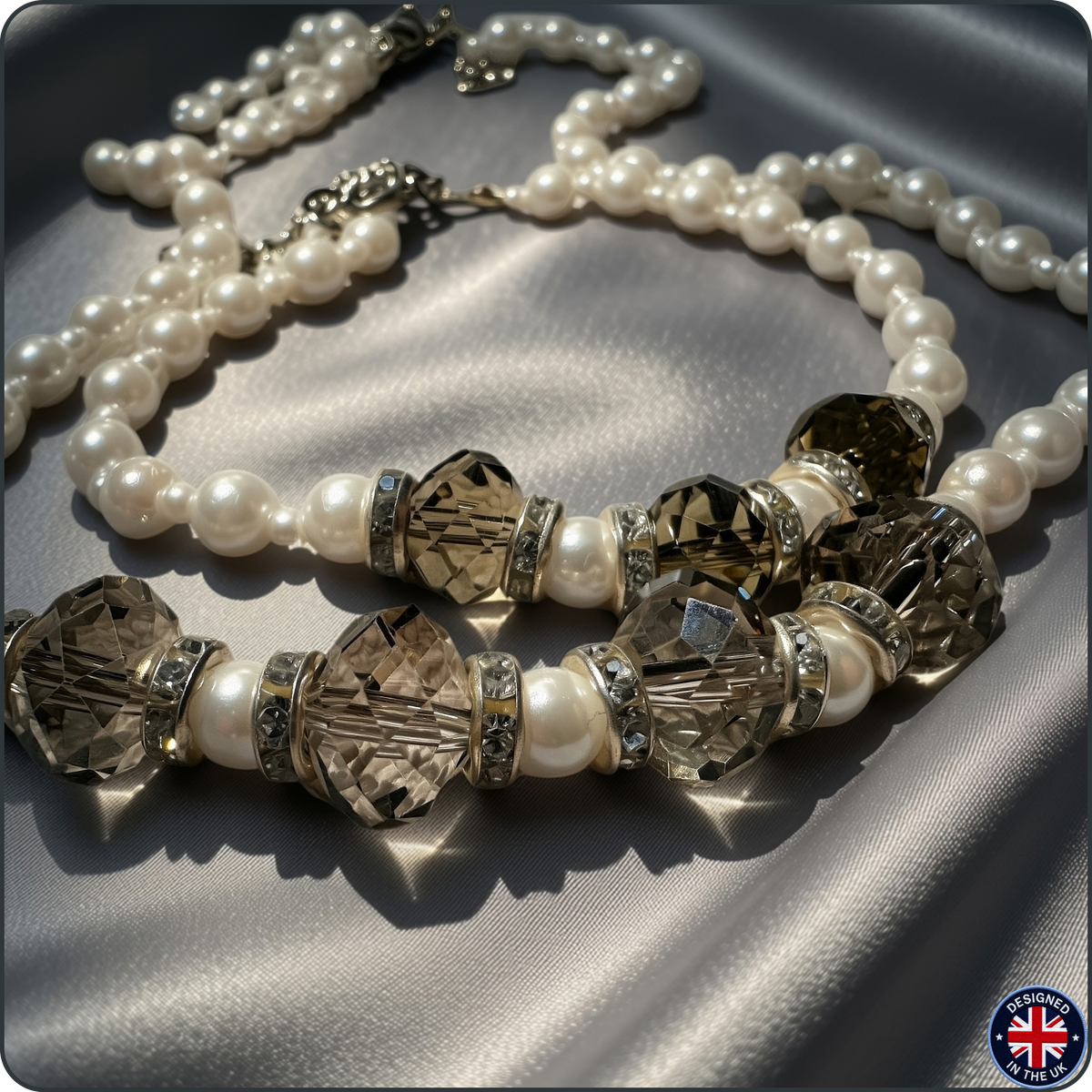 A double-strand pearl necklace with faceted crystal beads, displayed on draped satin fabric.