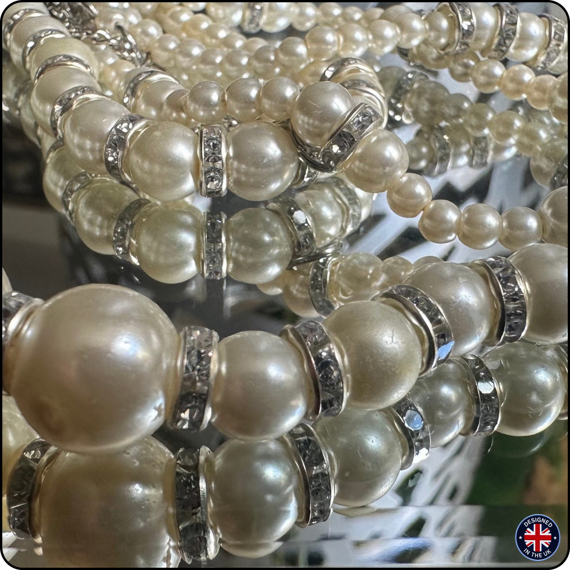 Close-up of multiple strands of pearl beaded bracelets with silver spacer rings, displayed on a reflective surface.