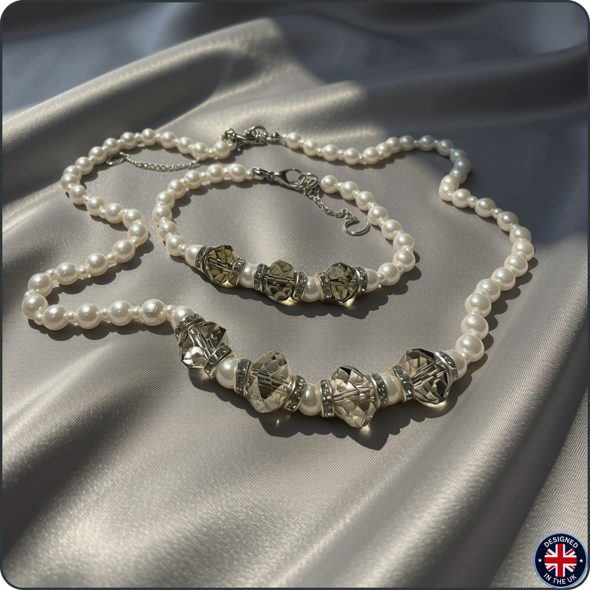 A pearl-bead necklace and matching bracelet with faceted crystal and metallic spacer beads, arranged on draped satin fabric.