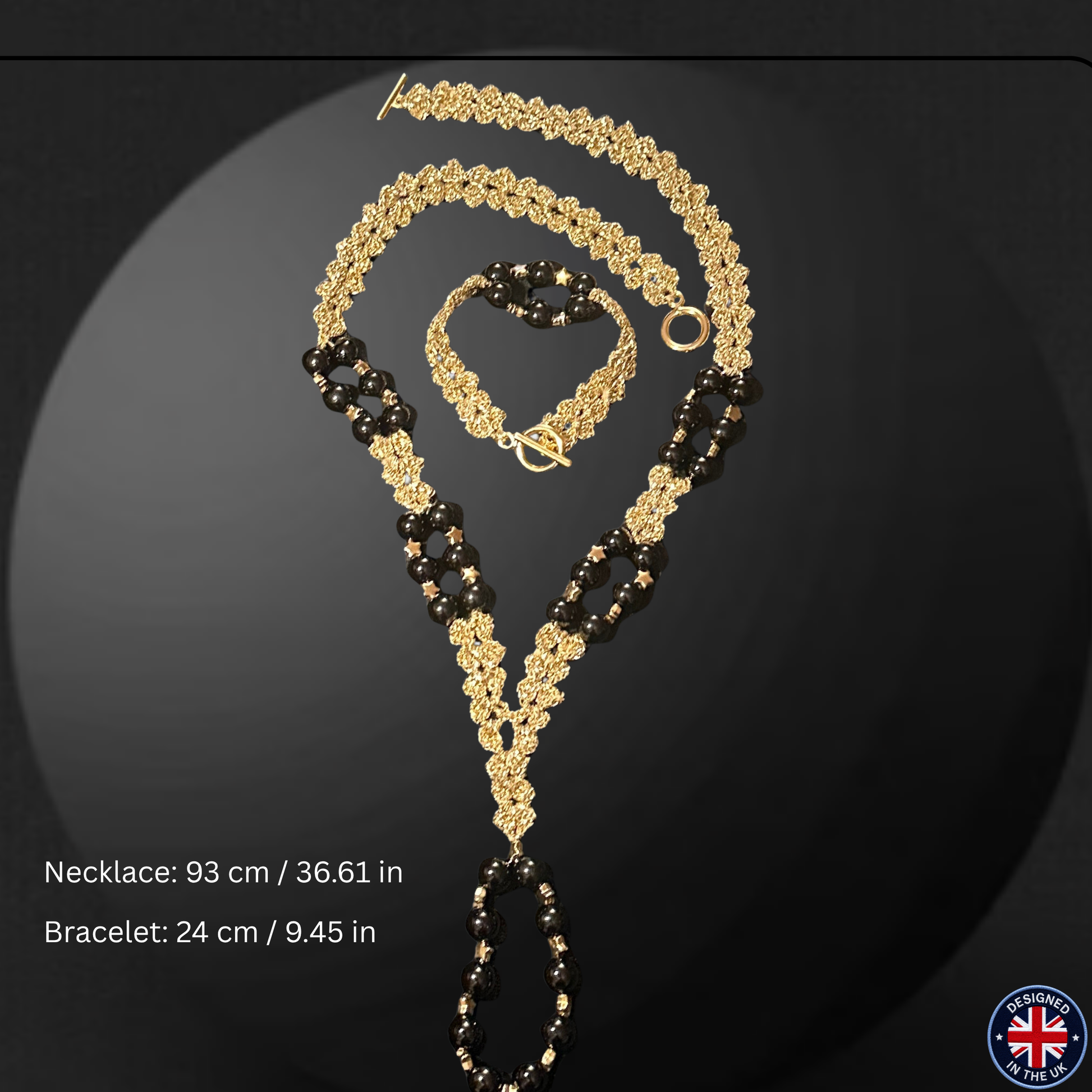 Gold and black beaded necklace and bracelet set displayed on a dark reflective surface, with text showing measurements: necklace 93 cm / 36.61 in and bracelet 24 cm / 9.