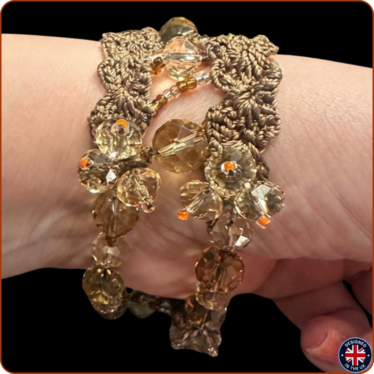A close-up of a handmade macrame bracelet with faceted clear beads and small orange accent beads, worn on a person's wrist against a black background.