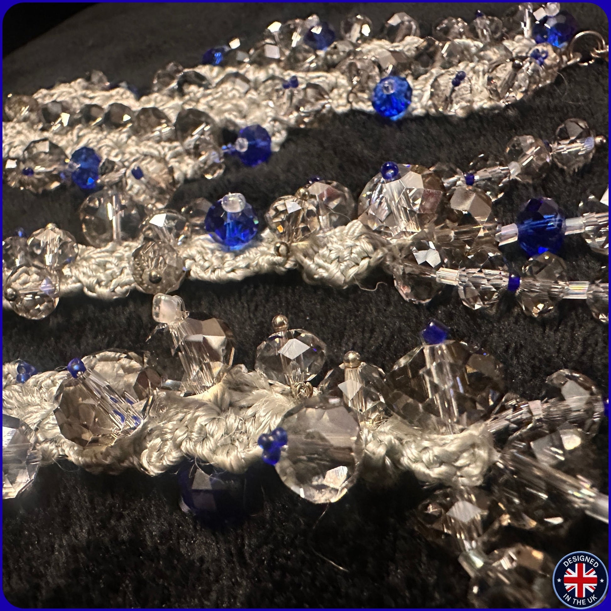 A close-up of a beaded trim or fringe featuring silver-toned beads, clear faceted crystal beads, and bright blue accent beads.