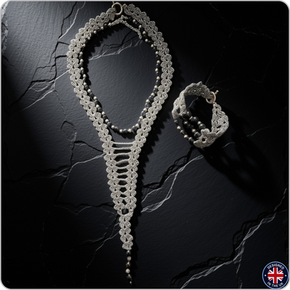 A silver-toned crochet lace jewelry set featuring a long necklace and a matching bracelet, displayed on a dark textured stone surface.