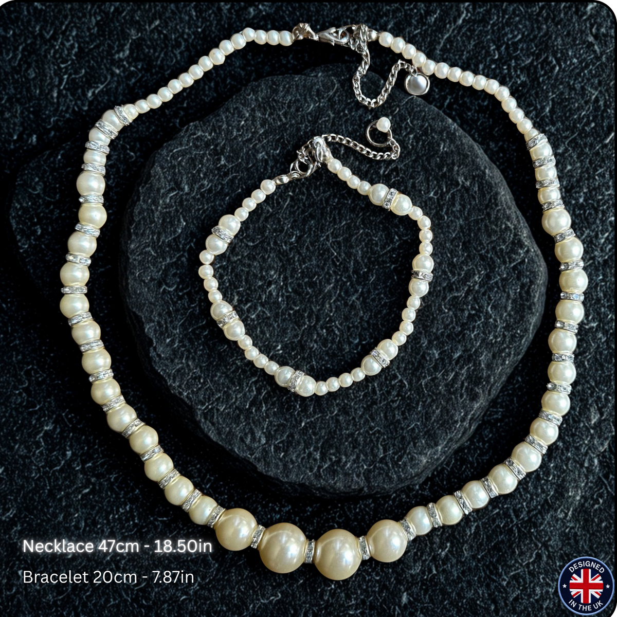 A pearl necklace and matching bracelet displayed on a dark textured stone surface. The necklace features cream-colored freshwater pearls with silver-toned spacer beads, and the bracelet is a smaller matching version.