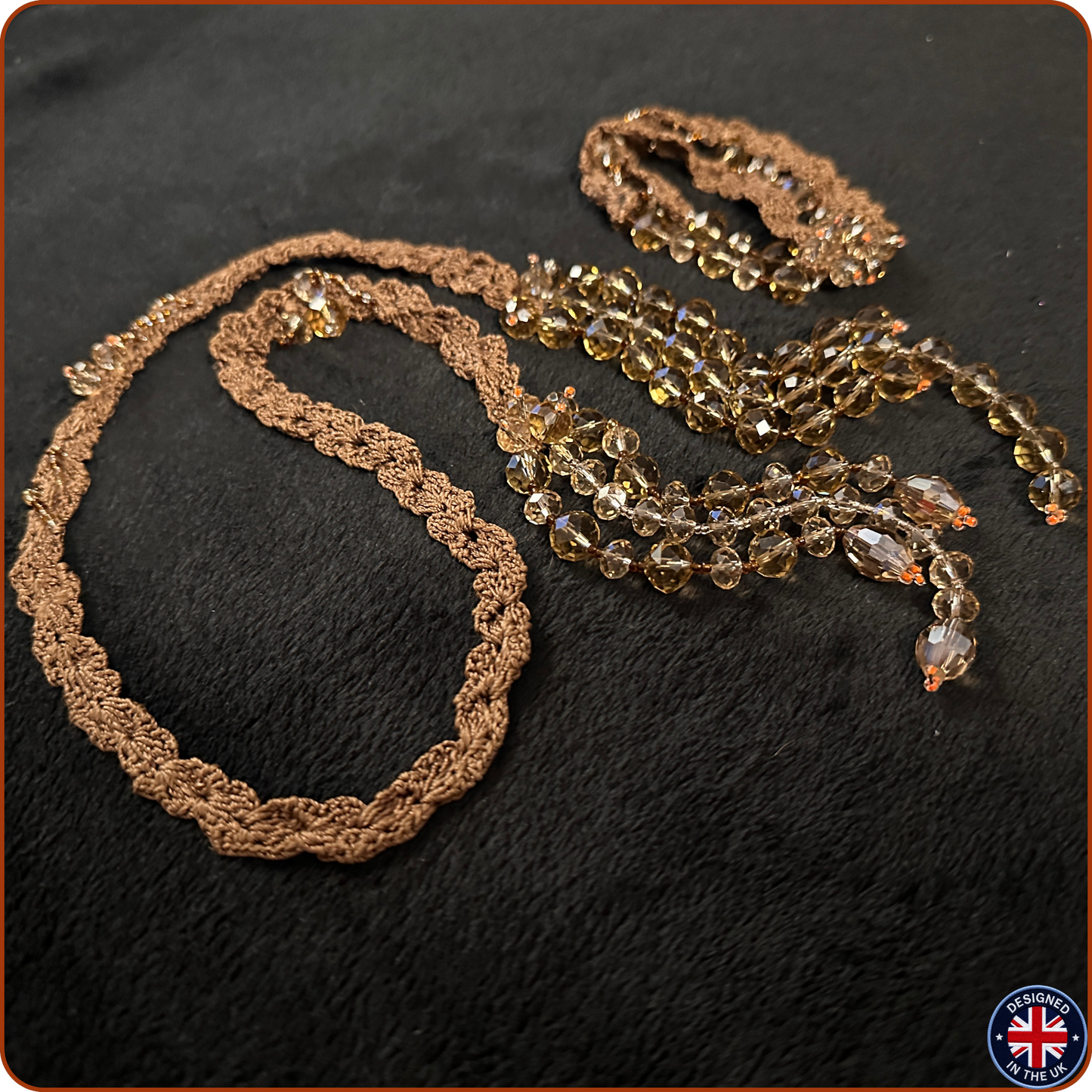 A vintage-style beaded necklace with a brown textured crochet or lace trim and cascading faceted amber-brown beads, displayed on a black textured fabric background.
