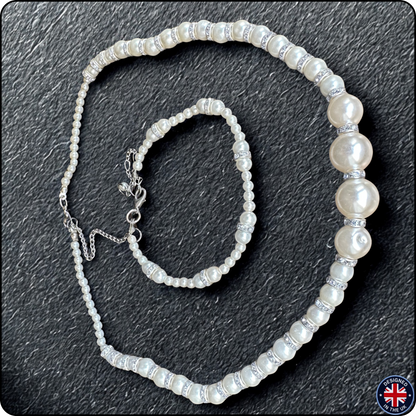 A pearl beaded necklace and matching bracelet set on a dark textured background. The beads are white with a lustrous pearl finish, separated by silver-toned spacer beads, and the necklace has an adjustable silver clasp.