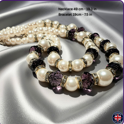 A pearl necklace and matching pearl bracelet with faceted dark purple crystal beads and silver tone spacer rings, arranged on draped satin fabric. 
