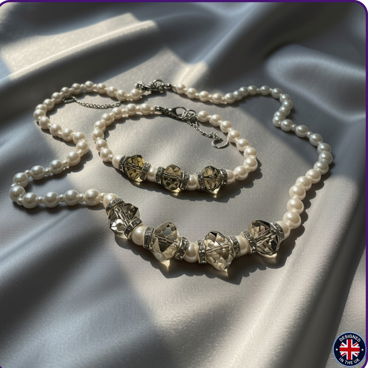 A pearl necklace with silver-toned chain and faceted clear beads, displayed on draped satin fabric. A matching pearl bracelet is also visible behind the necklace.