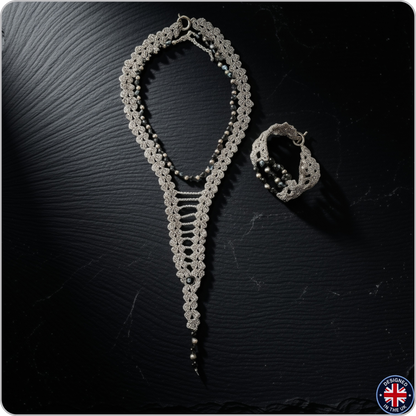 A silver-toned crochet jewelry set featuring a long beaded necklace and a matching bracelet, displayed on a dark textured background.