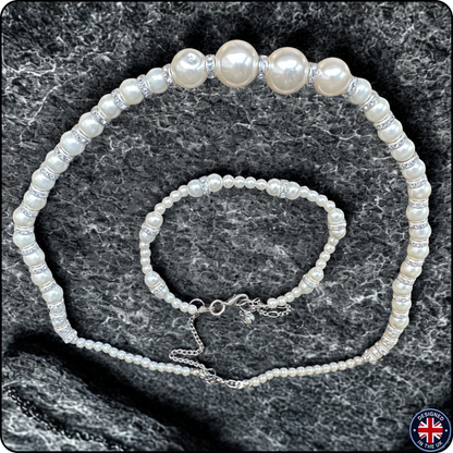 A pearl jewelry set consisting of a choker necklace and a matching bracelet, both featuring white freshwater-style pearls and silver-toned spacer beads, displayed on a dark gray textured stone background.