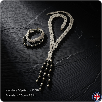 A silver-toned beaded necklace and matching beaded bracelets displayed on a dark textured background. Text at the bottom reads 'Necklace 55/42cm - 21/16in' and 'Bracelets 20cm - 7.