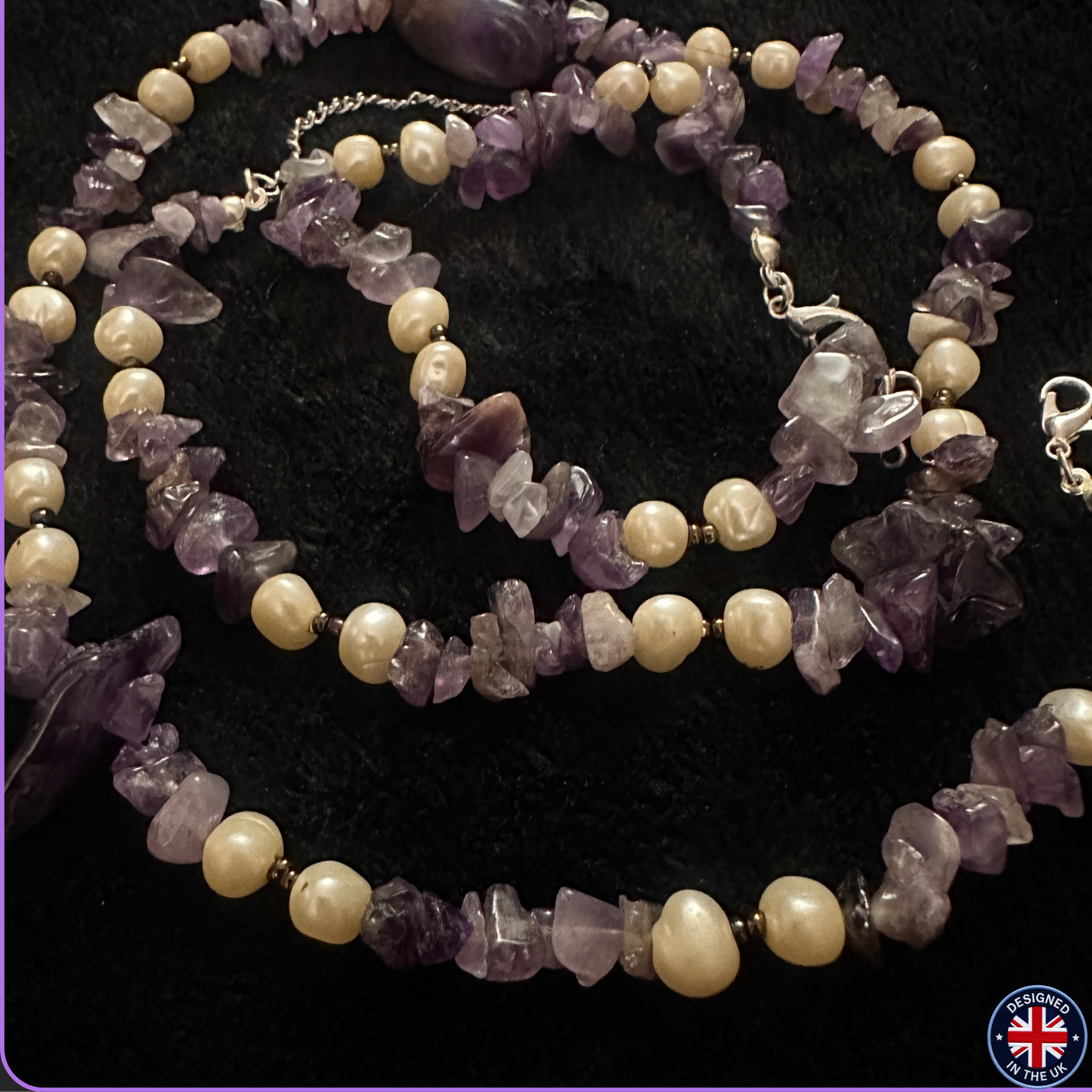A beaded necklace featuring irregular purple amethyst chips and cream-colored freshwater pearls separated by small gold spacer beads, displayed on a black textured background.