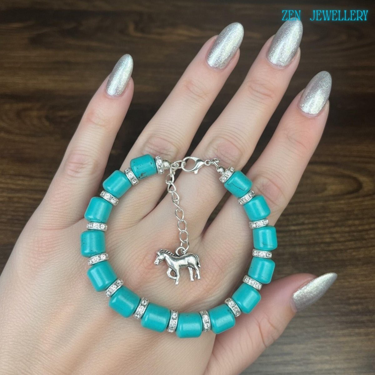 Handmade turquoise bracelet with smooth cylindrical beads in vibrant aqua blue tones, paired with silver rhinestone rings and a delicate silver horse charm for a stylish cowgirl-inspired jewellery look.