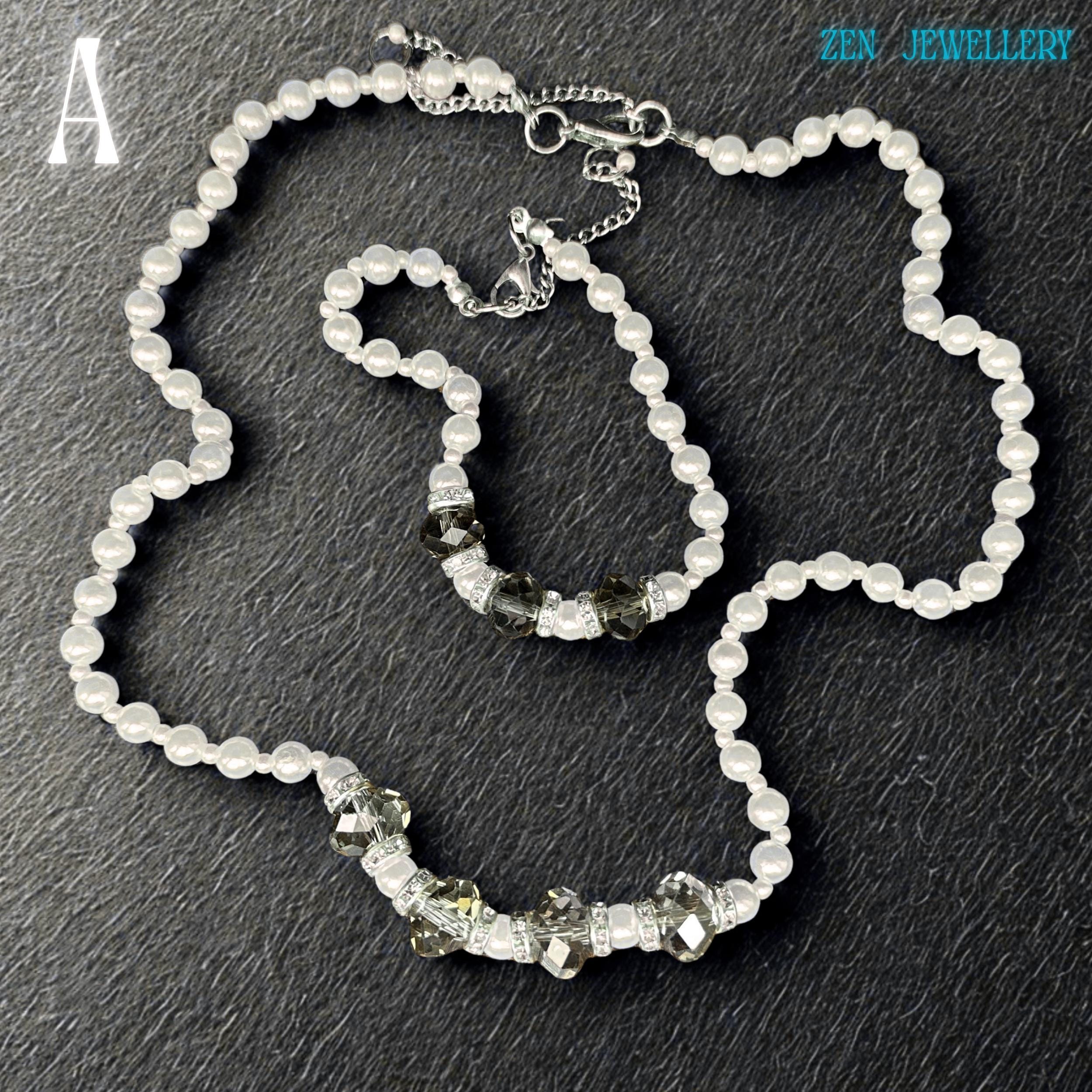 Close-up image of a handmade white pearl jewellery set with faceted grey crystal beads and silver spacer details. The glossy pearl beads reflect light beautifully and create a soft luxurious appearance. The bracelet perfectly matches the necklace and includes sparkling rhinestone spacers that add elegant shine and contrast. The dark background enhances the brightness of the pearls and the sparkle of the crystals.
