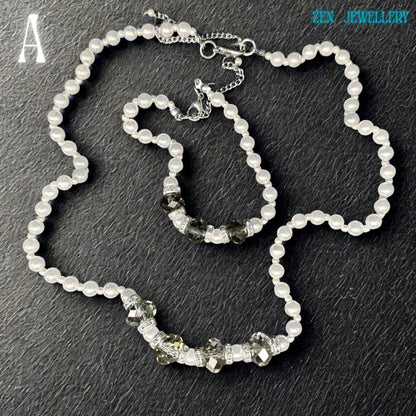 Close-up image of a handmade white pearl jewellery set with faceted grey crystal beads and silver spacer details. The glossy pearl beads reflect light beautifully and create a soft luxurious appearance. The bracelet perfectly matches the necklace and includes sparkling rhinestone spacers that add elegant shine and contrast. The dark background enhances the brightness of the pearls and the sparkle of the crystals.