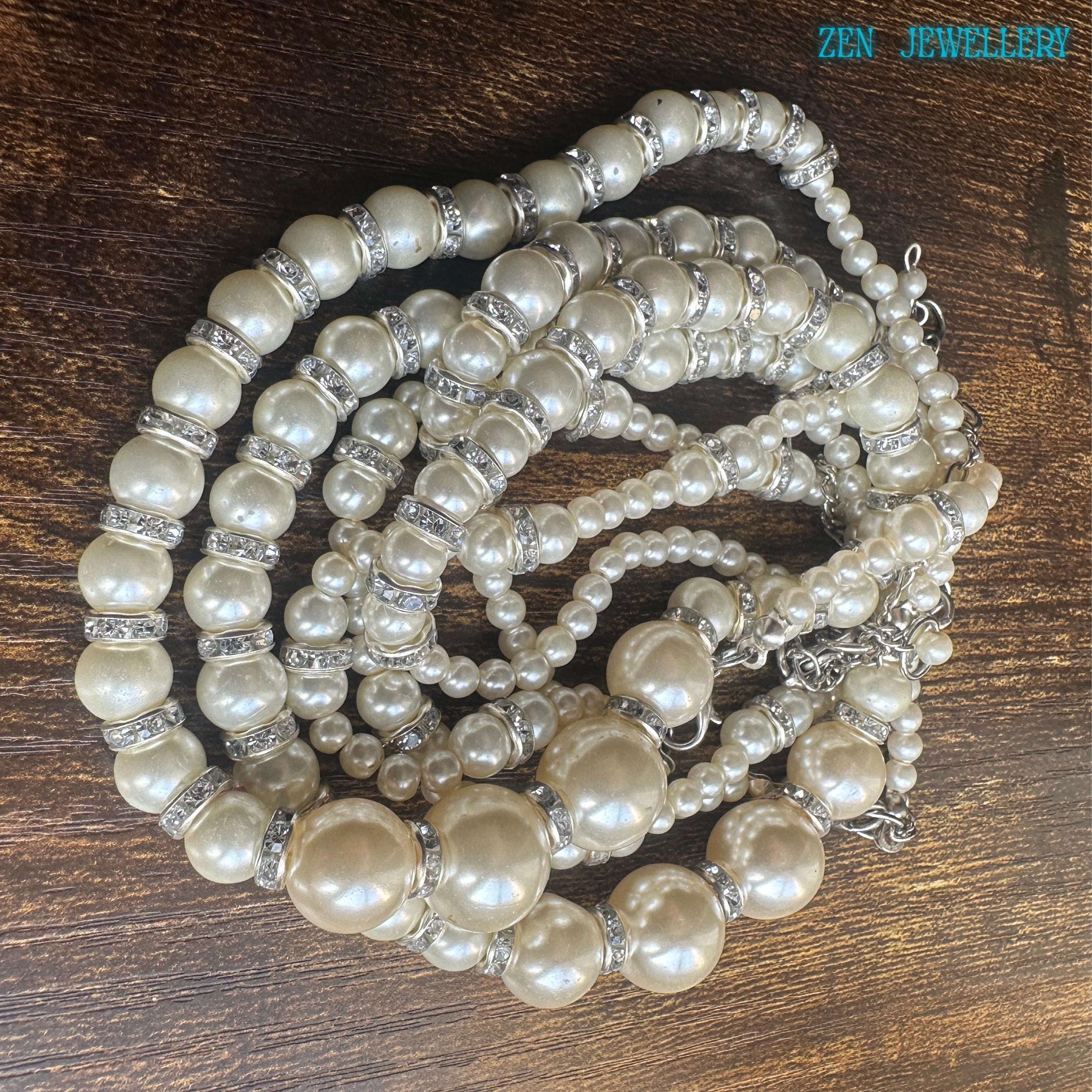 Detailed texture of smooth white pearl beads with reflective rhinestone spacers adding sparkle.