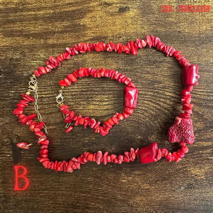 Elegant coral jewellery set photographed on a decorative silver tray to highlight the contrast between vivid red coral chips and warm gold chain details. The handcrafted bead arrangement gives the necklace and bracelet an artisan appearance with movement, texture, and bold visual impact.