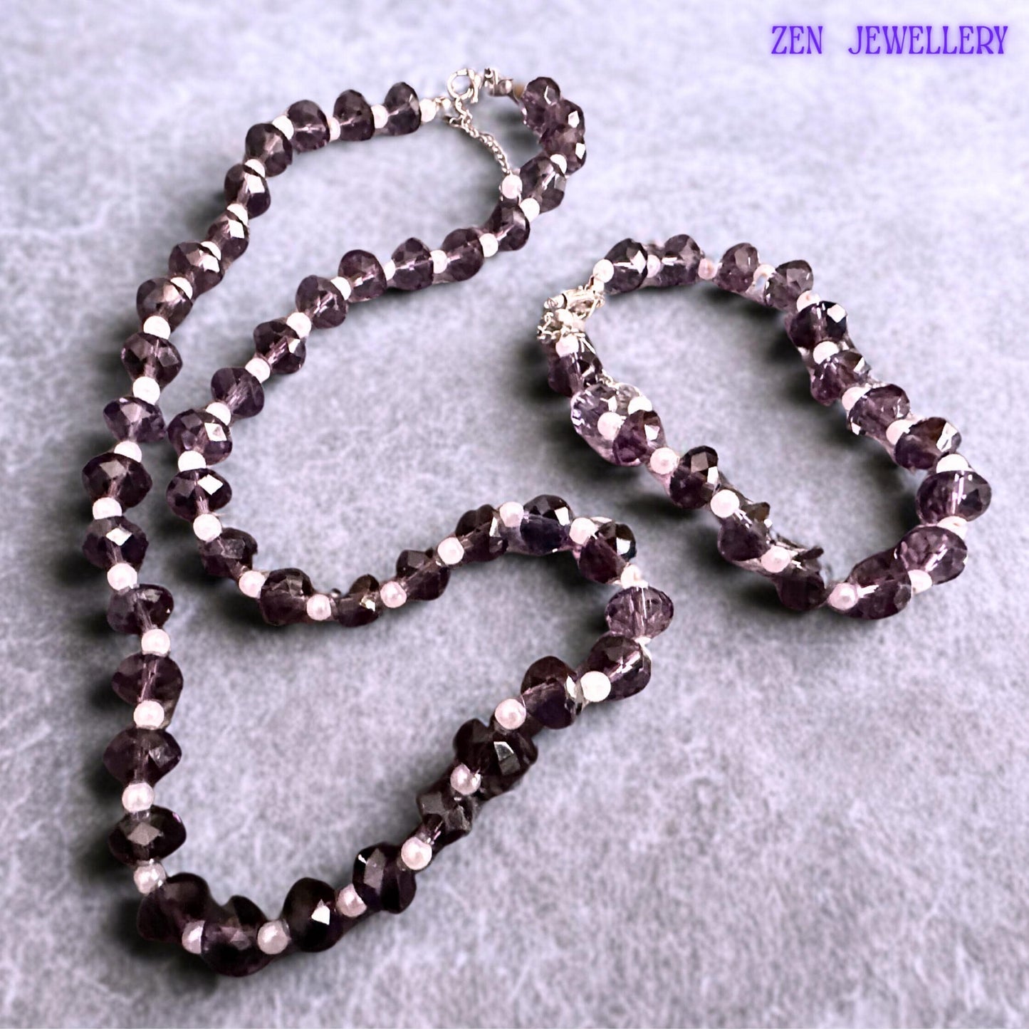 Matching purple crystal bracelet and necklace set designed with faceted lavender beads creating texture sparkle and elegant movement paired with white pearl accents and silver extension chains for adjustable comfortable wear.