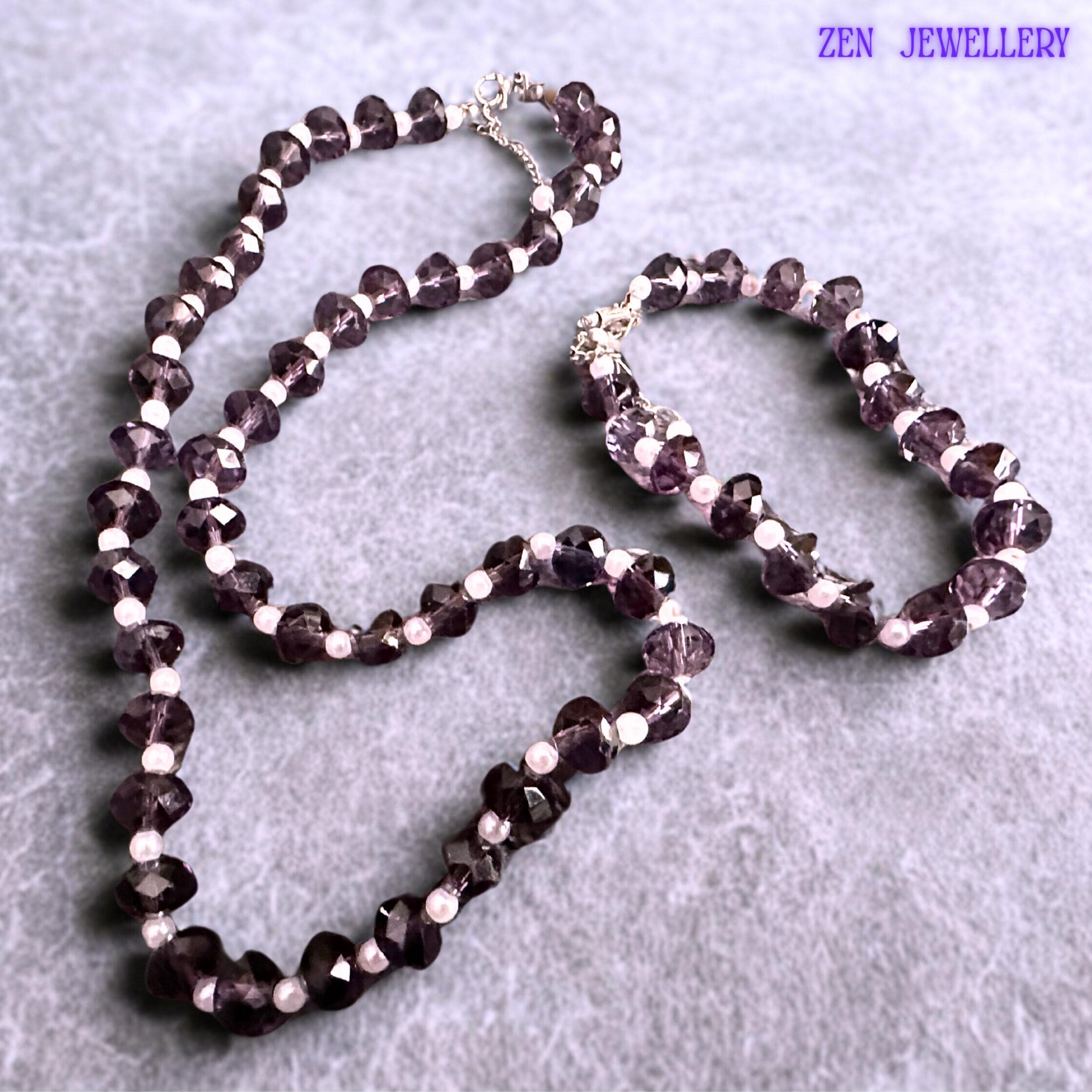 Matching purple crystal bracelet and necklace set designed with faceted lavender beads creating texture sparkle and elegant movement paired with white pearl accents and silver extension chains for adjustable comfortable wear.