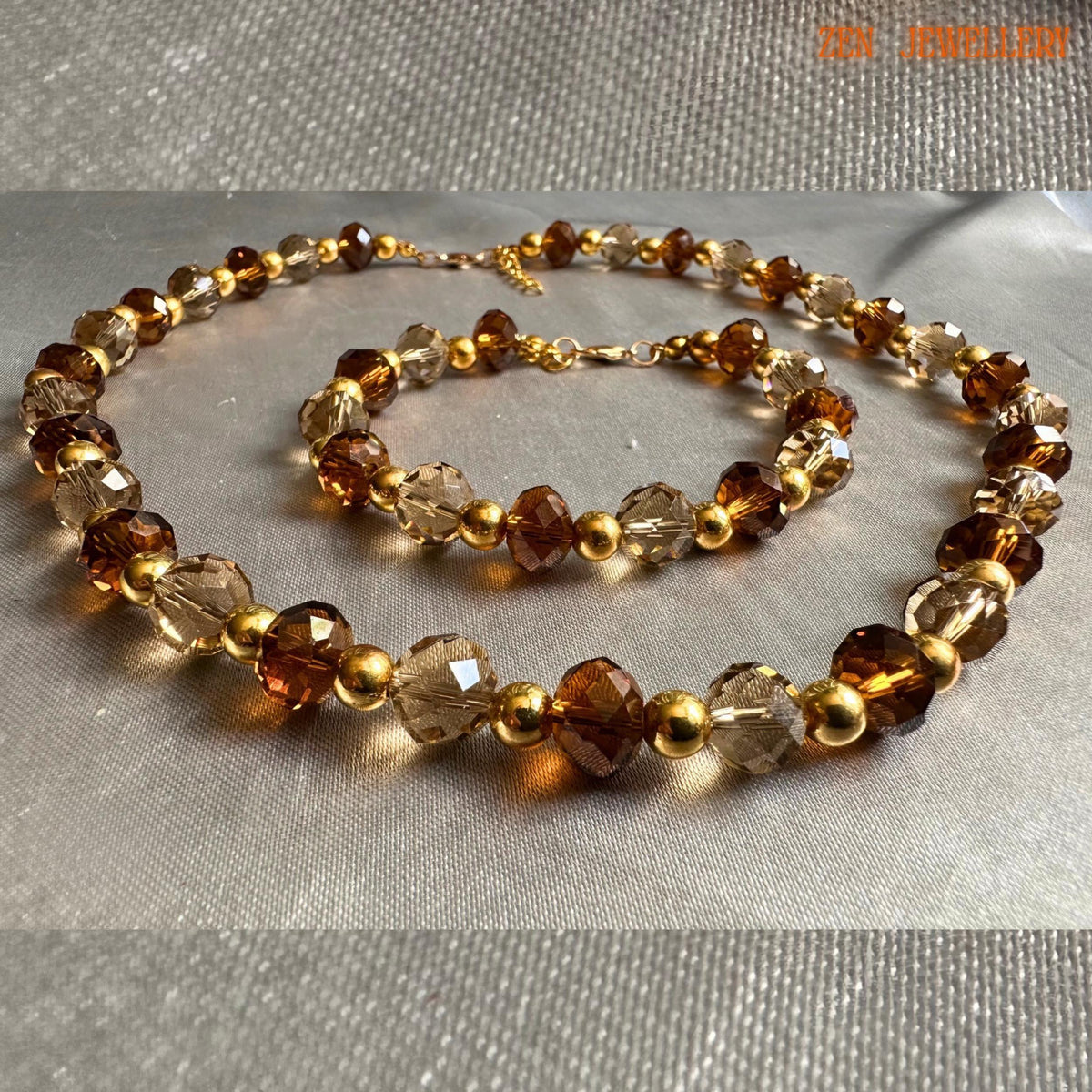 Glamorous handmade necklace and bracelet set featuring faceted amber crystal beads in warm caramel and honey shades combined with metallic gold spacer beads for an elegant evening jewellery look. The jewellery appears lightweight, feminine, and perfect for formal fashion styling or festive occasions.