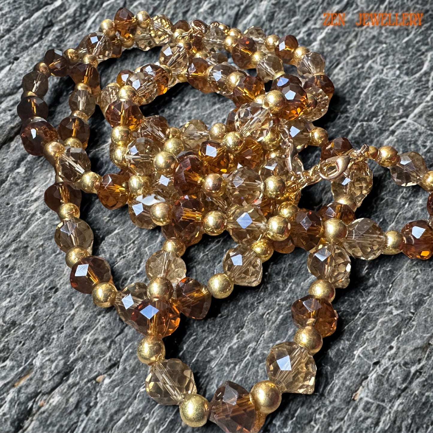 Brown and champagne crystal necklace with gold beads and matching bracelet on neutral fabric