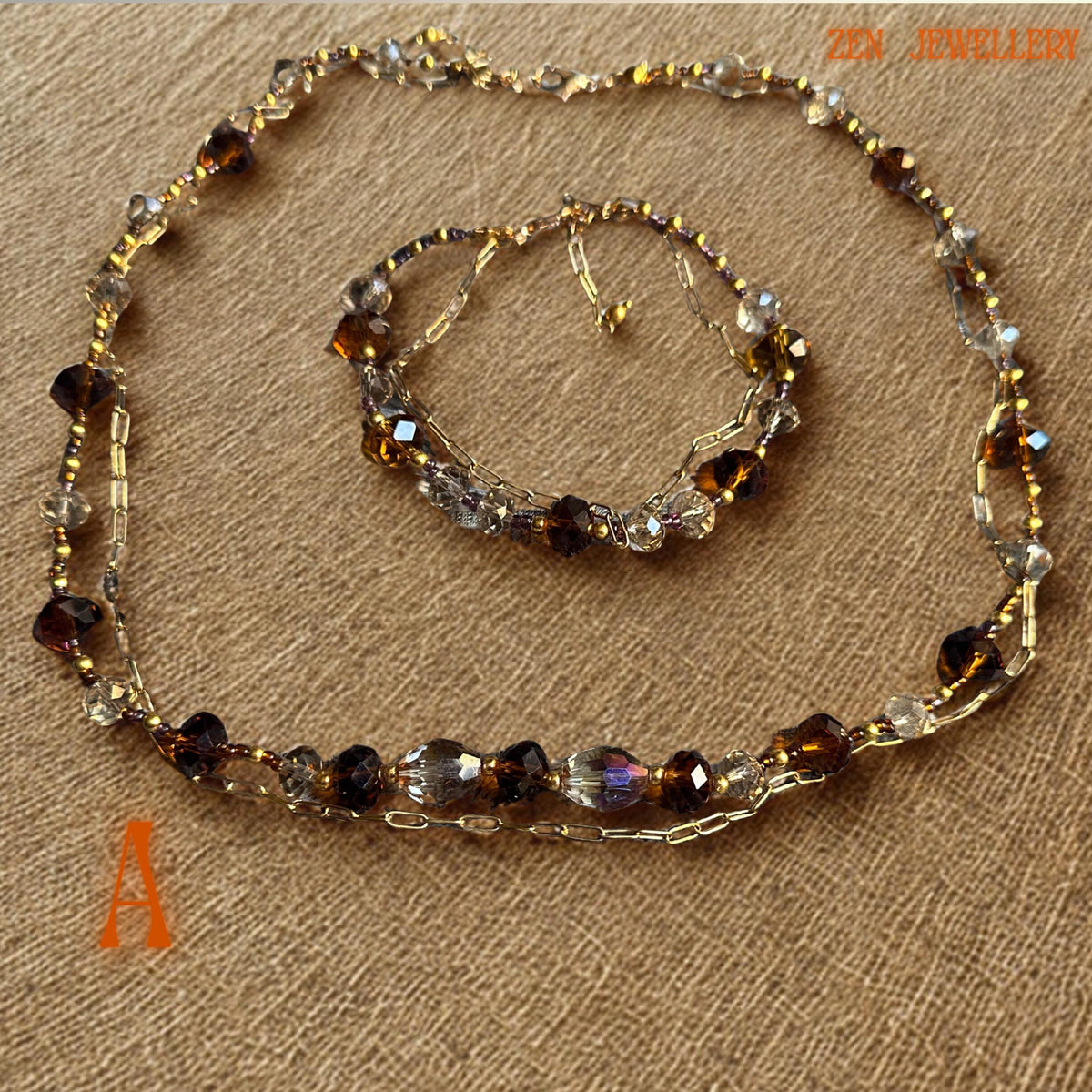 Detailed image showing faceted caramel and bronze Austrian crystal beads with reflective surfaces that shimmer under soft lighting. Gold spacer beads and elegant clasp details create a refined finish while the layered chain sections add texture and artistic movement. The matching bracelet complements the necklace perfectly and creates a coordinated luxurious jewellery look.