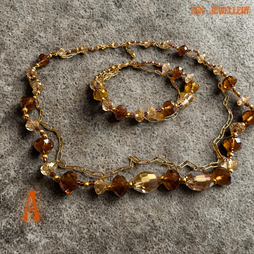Handmade champagne crystal necklace and bracelet displayed flat on textured beige fabric background. The warm caramel and golden brown crystals create a luxurious sparkling effect while the polished gold beads and chain details add refinement and contrast. The layered design creates elegant movement perfect for romantic fashion styling and festive outfits.