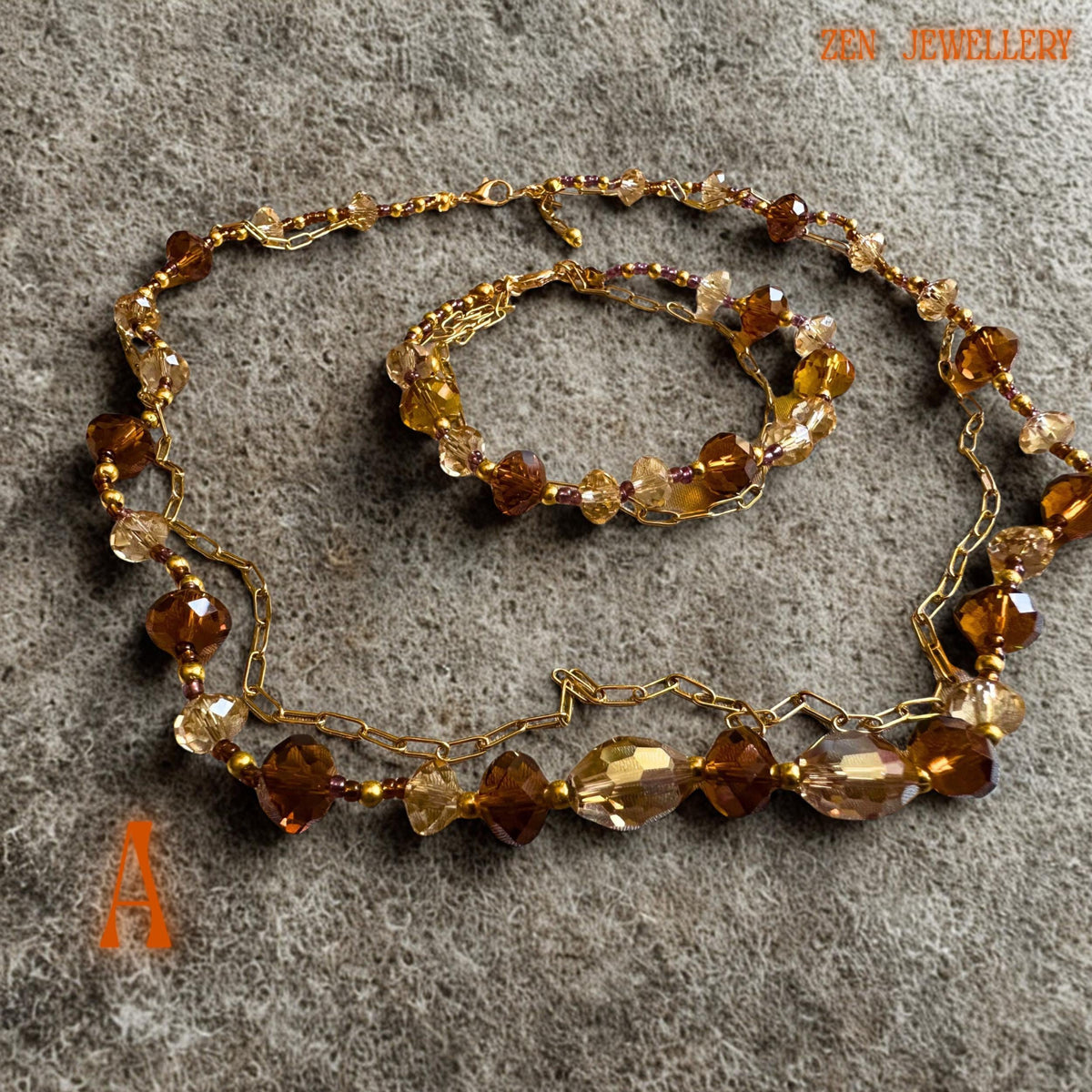 Handmade champagne crystal necklace and bracelet displayed flat on textured beige fabric background. The warm caramel and golden brown crystals create a luxurious sparkling effect while the polished gold beads and chain details add refinement and contrast. The layered design creates elegant movement perfect for romantic fashion styling and festive outfits.