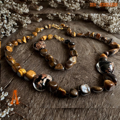 Close-up view of tiger eye gemstone beads with natural golden bands, polished surfaces, and rich honey-brown tones, paired with elegant gold chain links. The handmade necklace and bracelet set feels warm, earthy, and sophisticated with beautiful bohemian-inspired styling.
