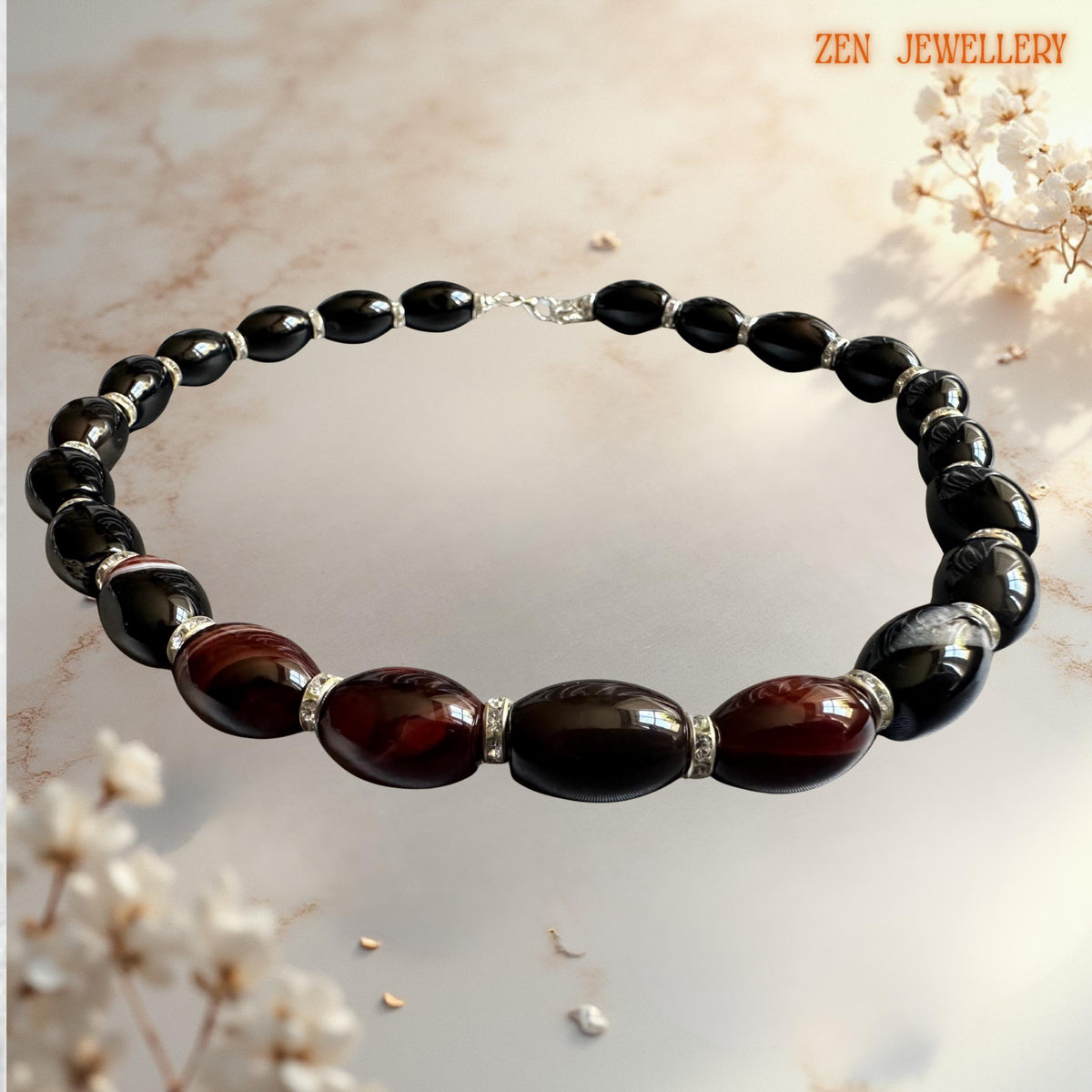 Elegant feminine agate gemstone necklace with glossy black oval beads and rich wine-red agate accent stones separated by sparkling rhinestone silver rings. The handcrafted jewellery design combines dramatic dark tones with luxurious silver details for an evening fashion look. Finished with a secure silver lobster clasp and adjustable chain. Necklace measures approximately 47 cm which equals 18.5 inches.