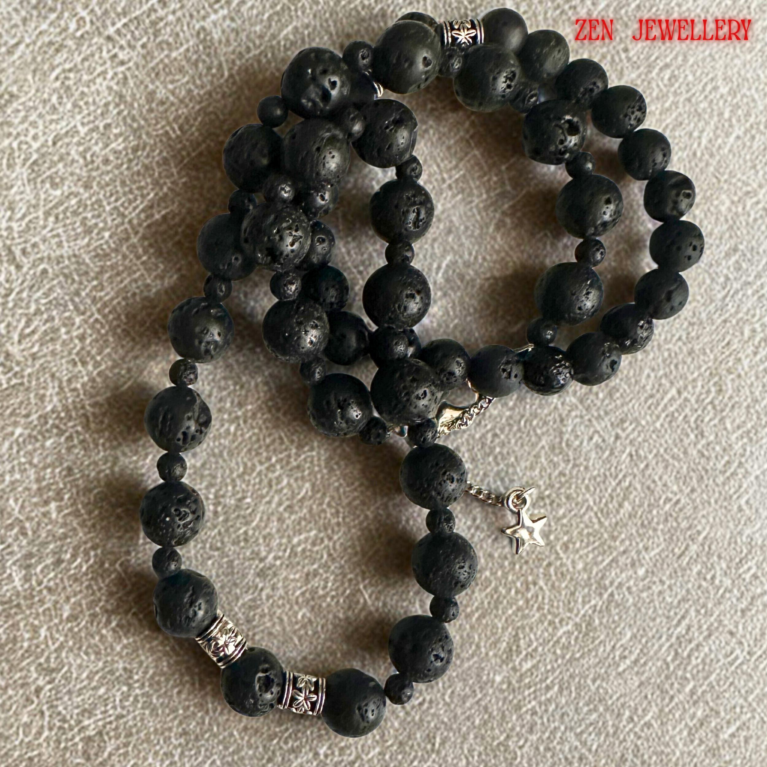Modern bohemian lava stone necklace and bracelet set designed with natural black volcanic beads and silver decorative spacer details. The textured matte stones create a strong earthy appearance while the silver accents add brightness and elegance. The necklace features varying bead sizes for dimension and balance, while the bracelet completes the coordinated minimalist jewellery look.