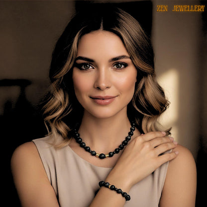 Detailed product photograph featuring a matching lava stone bracelet and necklace with golden decorative spacers and natural black volcanic beads. The porous matte stones create a raw earthy appearance while the gold details add sophistication and warmth. The bracelet complements the necklace perfectly with coordinated bead sizes and matching artisan details for a complete handmade jewellery set.