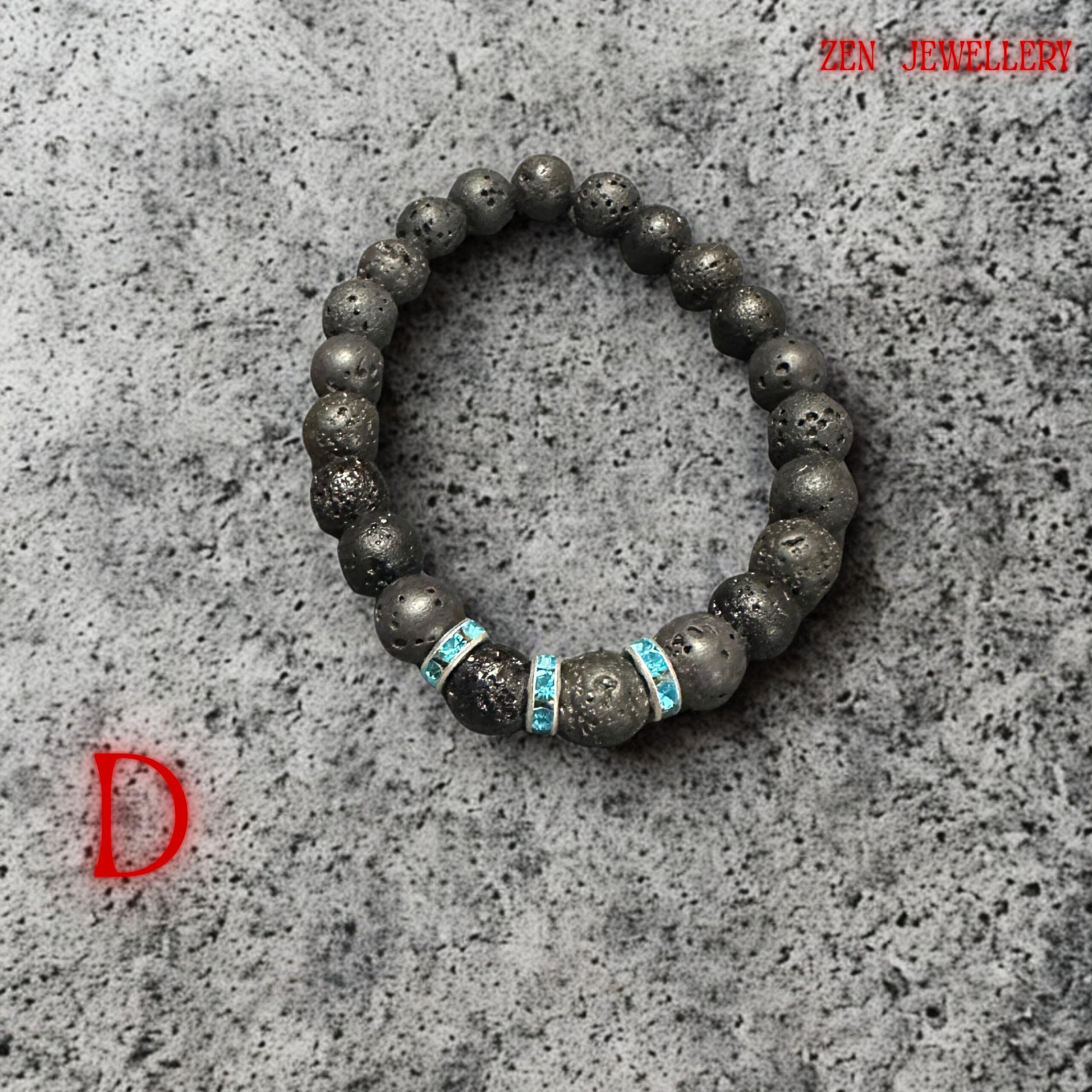 Black porous lava stone bracelet with elegant turquoise crystal spacer accents displayed on smooth spa pebbles, creating relaxing, zen-inspired styling. The handmade bracelet combines organic volcanic texture with modern bohemian elegance and subtle sparkle.