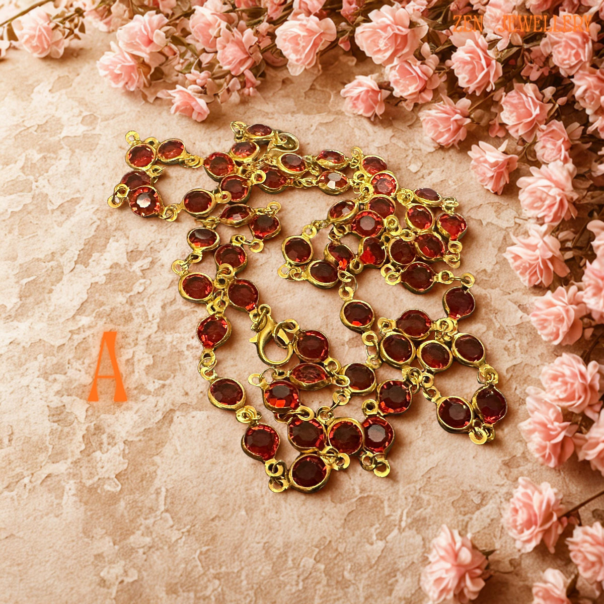 Elegant handmade crystal necklace and bracelet set displayed on a soft floral background featuring vibrant ruby red faceted crystals linked with delicate gold chain details. The rich crimson stones reflect warm light beautifully and create luxurious sparkle with every movement. Matching bracelet and necklace create a romantic coordinated jewellery look perfect for weddings, evening outfits, festive occasions, or feminine fashion styling. Necklace