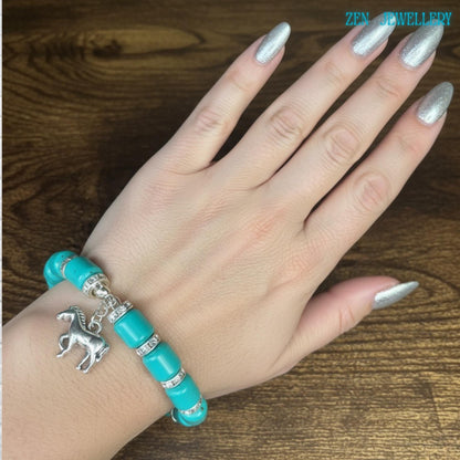 Close-up view of a turquoise bracelet with smooth glossy turquoise barrel beads and silver rhinestone spacer accents arranged evenly around the bracelet for an elegant and balanced handmade jewellery design.