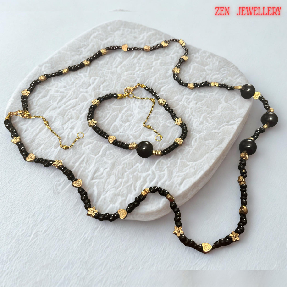Several larger round black agate beads serve as focal elements within the necklace and bracelet design. These statement stones add depth, dimension, and luxury while maintaining a cohesive appearance with the smaller surrounding beads. The photograph captures the smooth rounded shapes and glossy finish of the gemstones, allowing buyers to visualize the premium quality and elegant character of the handcrafted jewellery.
