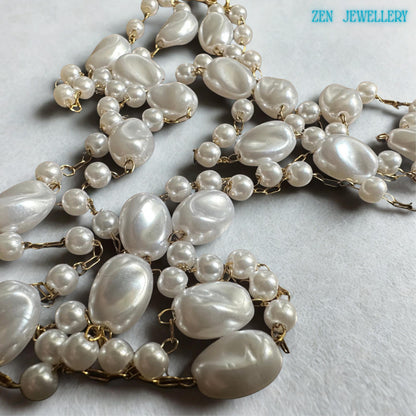 The white pearl necklace features oval beads spaced between tiny round pearl-style beads connected with delicate gold chain accents. The airy layered design creates graceful movement and a lightweight elegant appearance. The handmade necklace pairs beautifully with bridal outfits, wedding guest dresses, or everyday feminine styling.