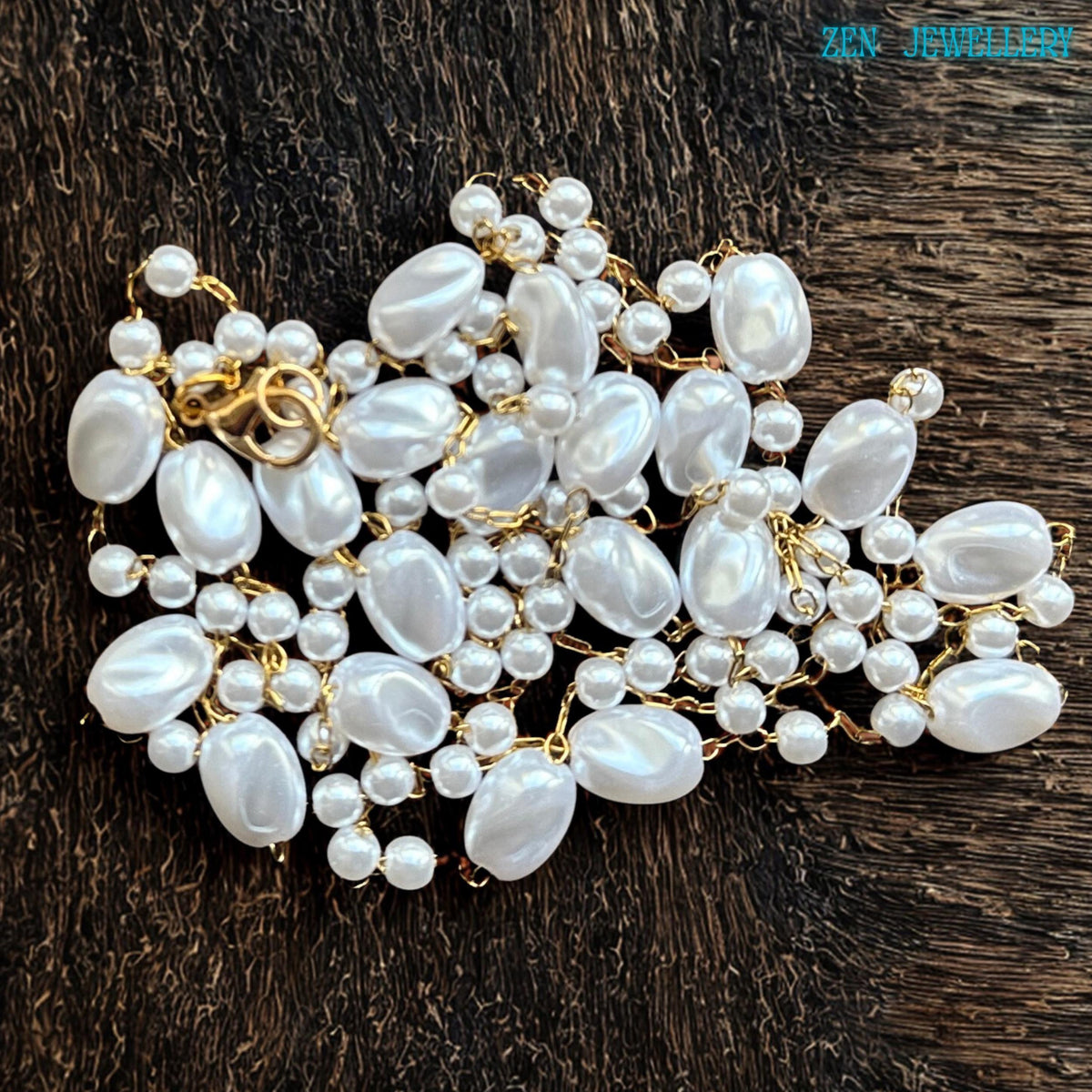 The elegant boho necklace features smooth white oval beads with smaller pearl-style beads carefully linked together using gold chain details. The handcrafted design creates balance and movement with an artistic asymmetrical arrangement. The glossy finish of the beads reflects light softly and adds a luxurious feminine touch.