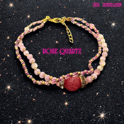 This close wrist view highlights the intricate arrangement of rose crystal beads in varying shades of blush pink and raspberry tones. Several strands flow together, combining polished round quartz beads with delicate seed bead sections accented by metallic gold details. The central faceted focal bead catches the light beautifully and is bordered by shimmering rhinestone spacers. The bracelet measures approximately 21 cm with an adjustable extende