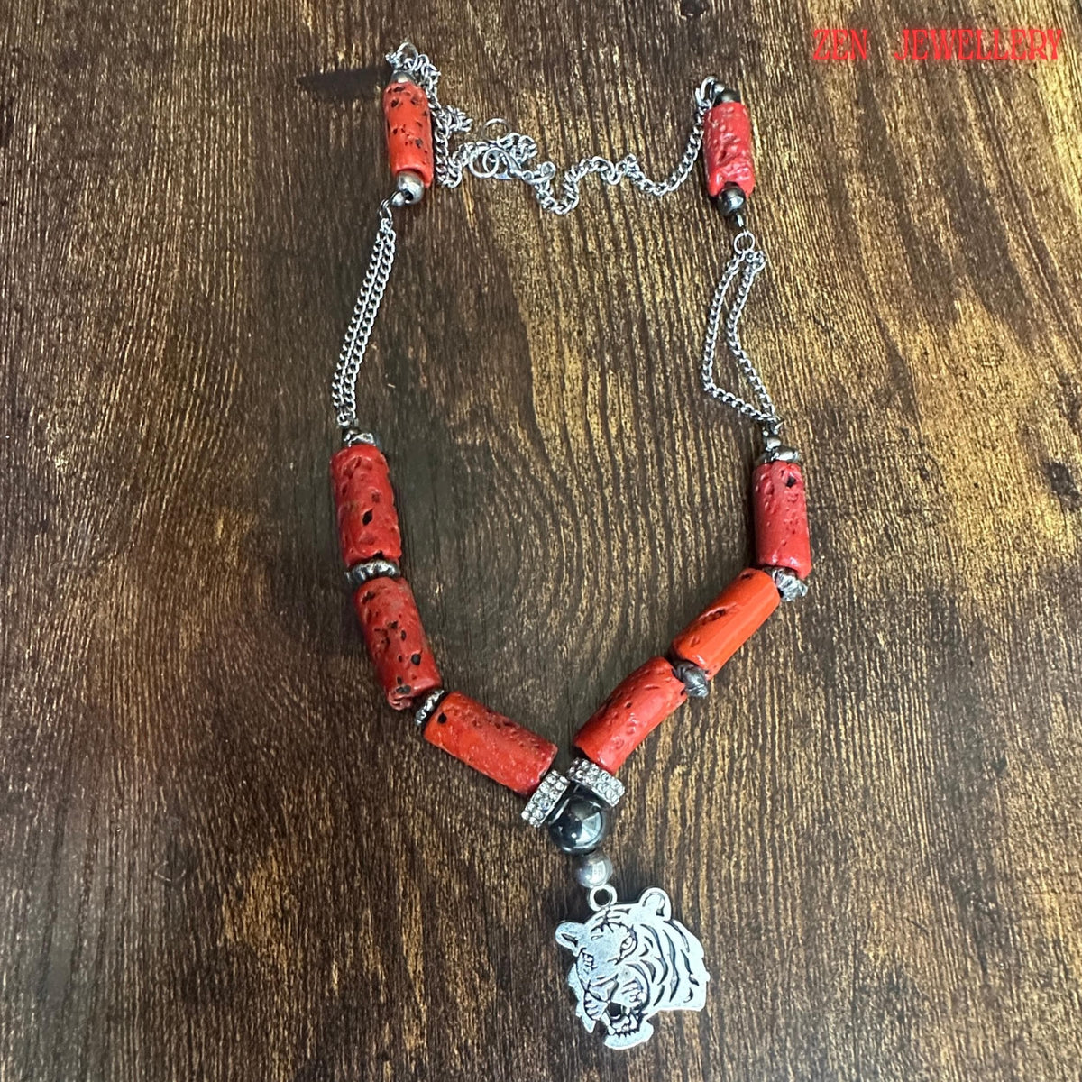 Side angle image of the coral baroque style necklace displaying the silver chain connections and natural cylindrical coral beads. The chunky red coral sections appear lightweight yet bold while the silver tiger charm provides an eye-catching focal detail. The necklace length measures approximately 58 cm and is suitable for casual or evening wear.