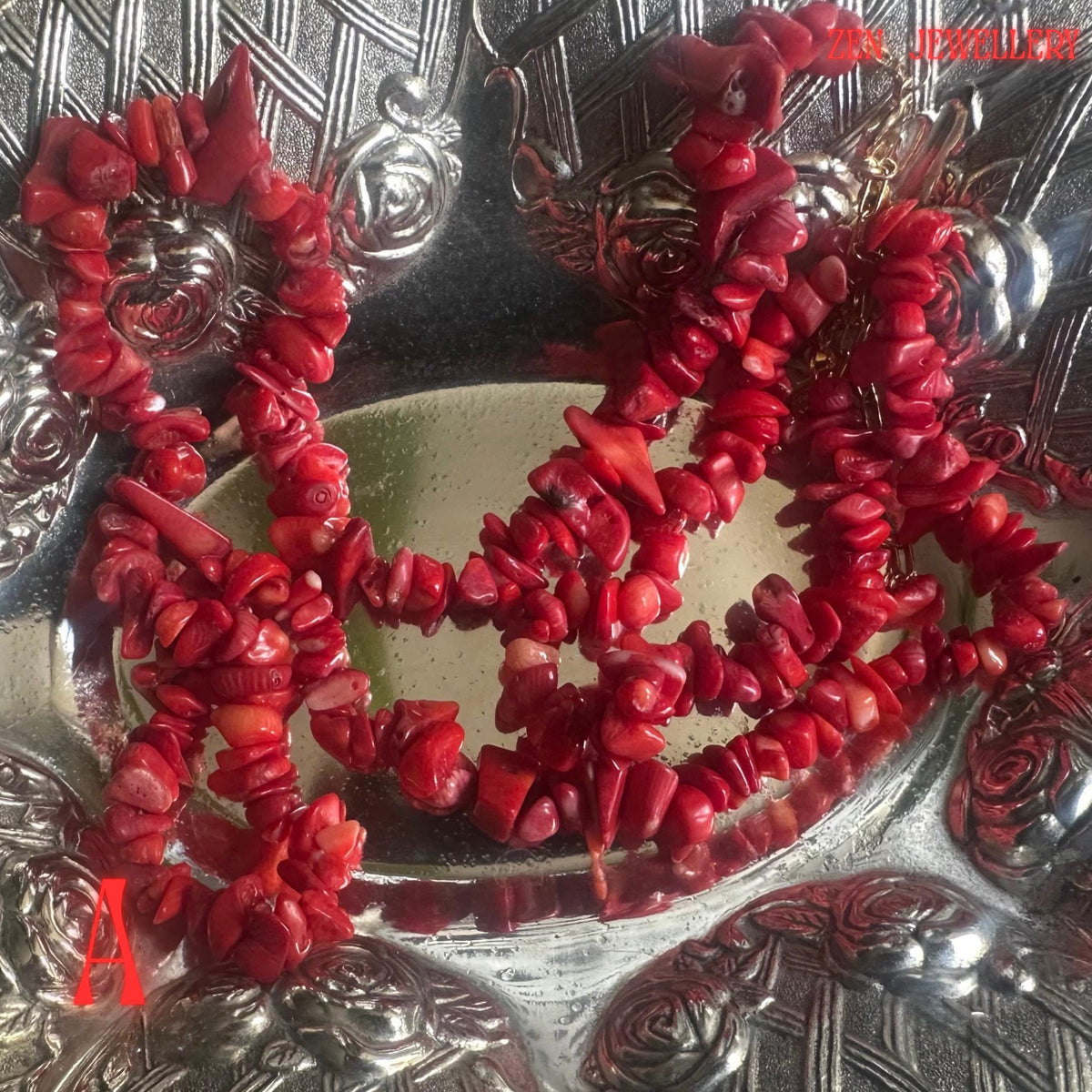 Handmade red coral statement necklace shown in close detail with rich coral-red tones and irregular gemstone chip textures arranged along the necklace strand. The matching bracelet complements the design perfectly and creates a coordinated handmade jewellery set suitable for gifts or occasion wear.