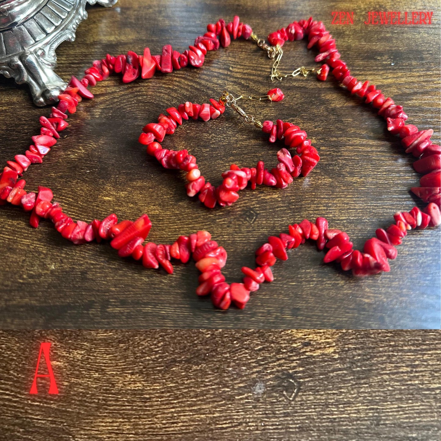 Detailed product image of the red coral necklace and matching bracelet showing polished coral chip textures in different natural shapes and sizes. The larger coral stones positioned throughout the set create contrast and dimension while the gold-tone chain and closures add a refined handmade finish.