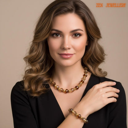 Detailed photograph showing warm brown crystal beads mixed with soft champagne crystal accents and polished gold details arranged in a coordinated necklace and bracelet jewellery set. The reflective faceted surfaces create elegant shine while the dark stone background enhances the luxurious crystal appearance.