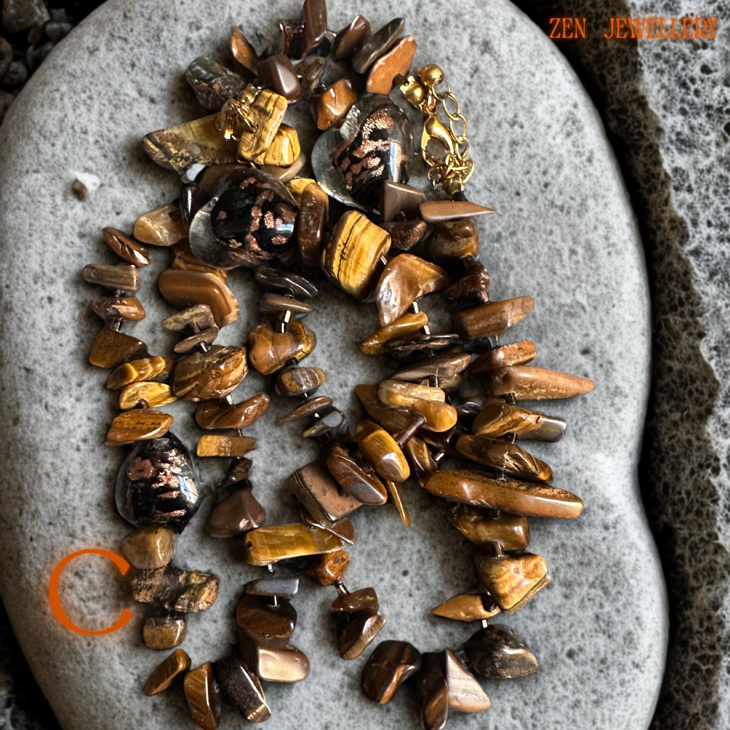 Close-up detail of polished tiger eye beads showing caramel, amber, and honey shades with natural reflective texture. The gold spacer beads and chain accents create contrast and add sophistication to the handmade jewellery set.