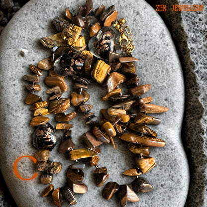 Close-up detail of polished tiger eye beads showing caramel, amber, and honey shades with natural reflective texture. The gold spacer beads and chain accents create contrast and add sophistication to the handmade jewellery set.